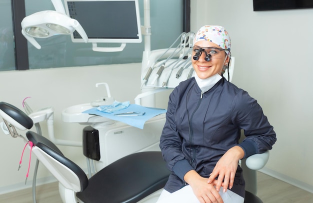 Bela dentista feminina sentada perto da cadeira odontológica