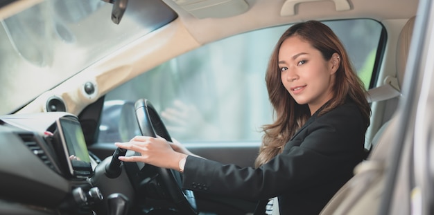 Bela empresária asiática profissional sorrindo enquanto dirigia o carro