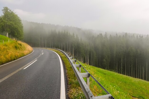 Bela estrada de montanha na Áustria. Floresta enevoada e céu nublado no fundo.