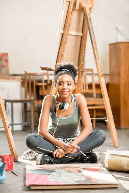 Bela estudante de etnia africana pintando no chão da sala de aula da universidade