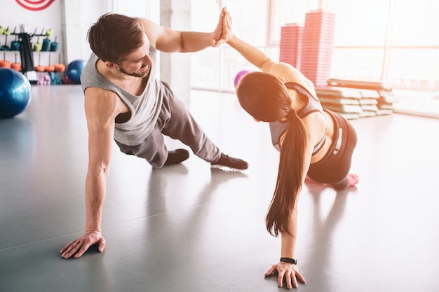 Bela foto de menino e menina em pé em uma posição de prancha lateral e dando mais cinco para o outro.