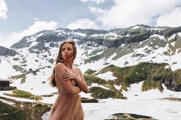 Bela foto de uma mulher caucasiana em um vestido elegante posando em montanhas nevadas