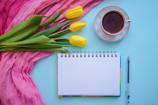 Bela foto romântica com bloco de notas, chá e tulipas em fundo azul