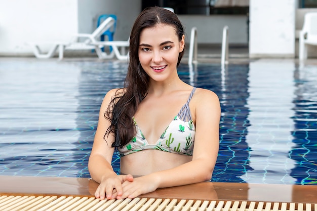 Bela garota caucasiana sexy sorrindo e sexy de biquíni em volta da piscina.