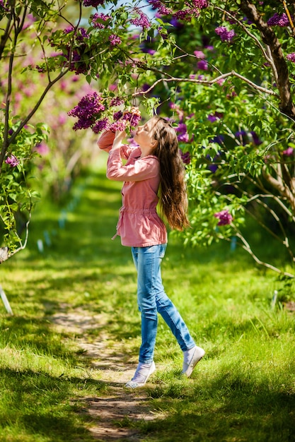 Bela garota desfrutando de jardim lilás