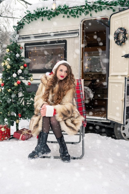 Bela garota disfarçada de Papai Noel com uma caixa de presentes no acampamento de inverno