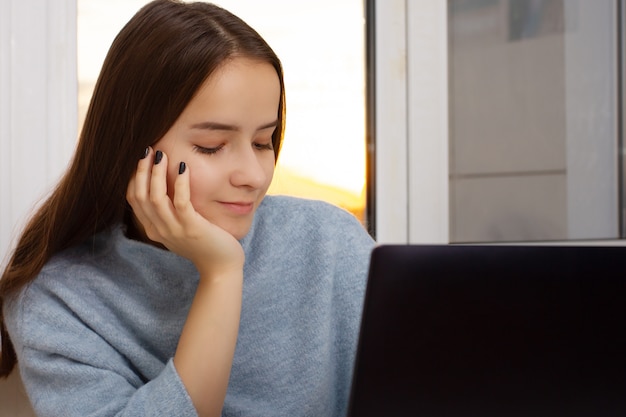 Bela garota Europeia em casa sentado em um laptop, trabalhando, compras