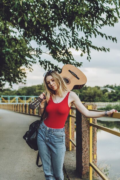 Foto bela garota loira com guitarra retrato ao ar livre jovem mulher tocando guitarra na rua da cidade