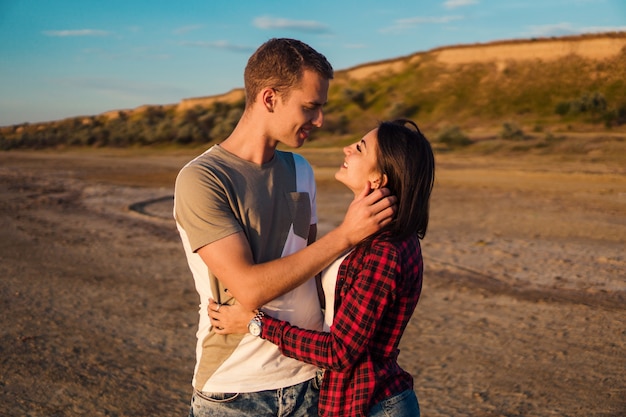 Bela história de um jovem casal lindo na praia no pôr do sol. eles estão se beijando