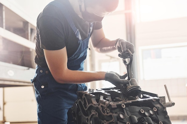 Bela iluminação Reparador profissional em máscara protetora preta trabalha com motor de automóvel quebrado