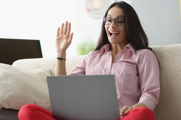 Bela jovem acenar olá mostrar gesto on-line no laptop