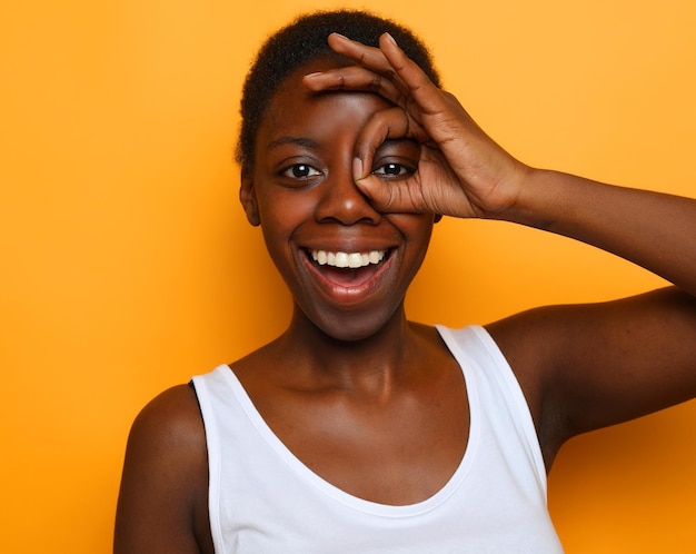 Bela jovem africana feliz isolada sobre fundo amarelo