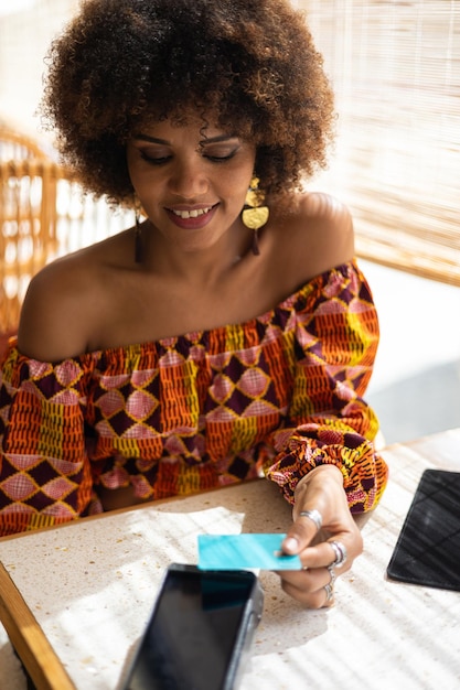 Bela jovem africana pagando com cartão de crédito em um restaurante