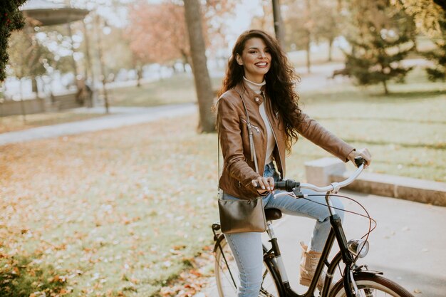 Bela jovem andando de bicicleta em dia de outono