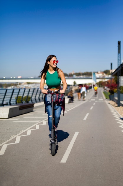 Bela jovem andando de scooter elétrico na rua