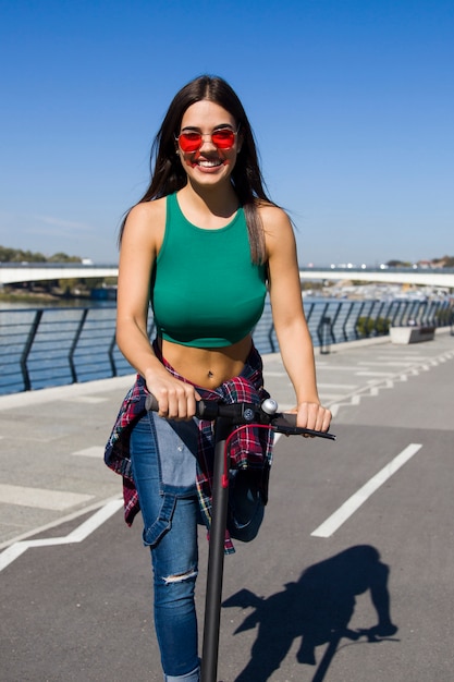Bela jovem andando de scooter elétrico na rua
