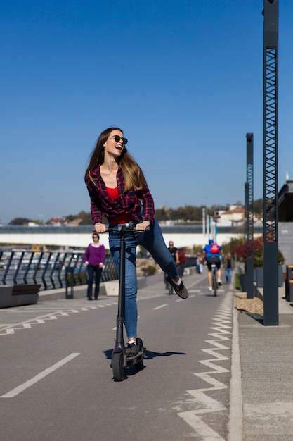 Bela jovem andando de scooter elétrico na rua