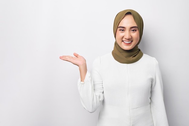 Bela jovem árabe muçulmana asiática sorridente usando hijab em pé apontando as mãos para o lado no espaço da cópia de maquete enquanto olha para a câmera no fundo branco Conceito de estilo de vida religioso de pessoas