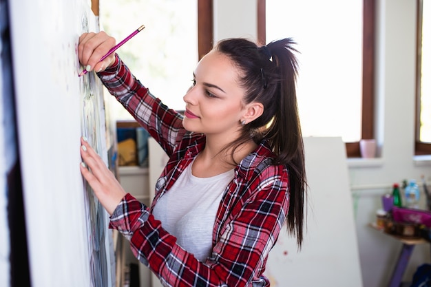 Bela jovem artista trabalhando em pintura em estúdio