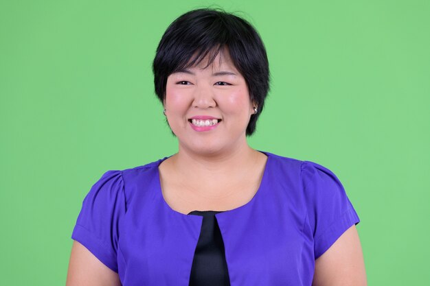 bela jovem asiática com excesso de peso contra chroma key com parede verde