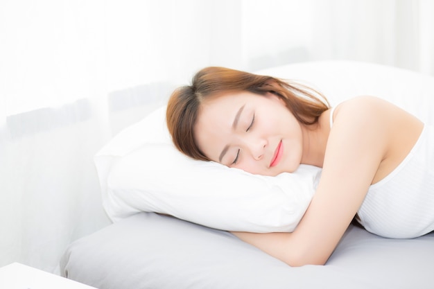 Bela jovem asiática dormindo deitada na cama com a cabeça no travesseiro