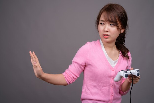 Bela jovem asiática jogando com o controlador de jogo