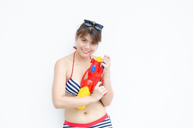 Bela jovem asiática segurando pistola de água e sorriso no dia do festival Songkran na Tailândia