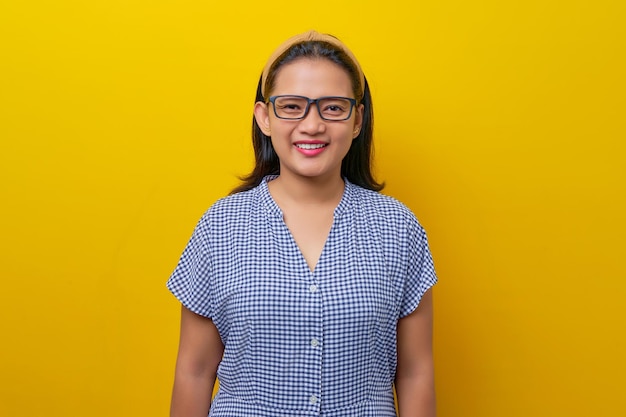 Bela jovem asiática sorridente usando um vestido xadrez sorrindo confiante para a câmera isolada no conceito de estilo de vida de pessoas de fundo amarelo