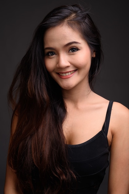 Bela jovem asiática sorrindo contra o cinza