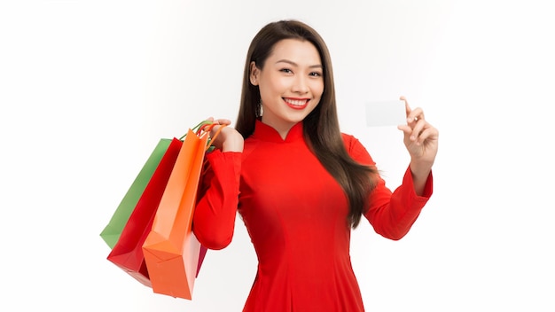 Bela jovem asiática usa vestido tradicional vietnamita vermelho com a mão segurando o cartão de crédito para mostrar confiança para fazer o pagamento