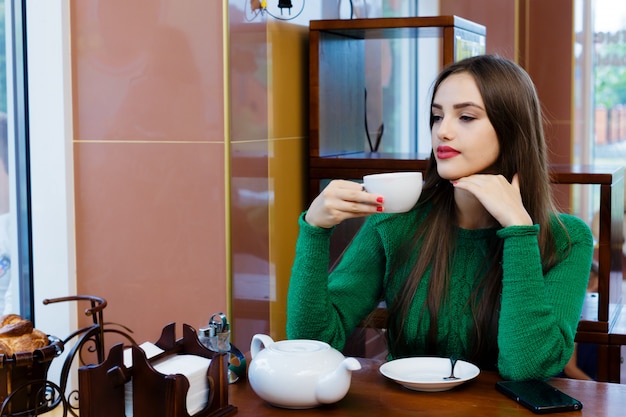 Bela jovem bebendo chá no café