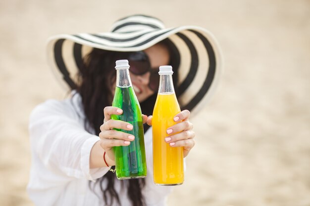 Bela jovem bebendo cocktail na praia. Garota atraente, oferecendo uma bebida. Linda mulher bebendo limonada