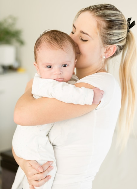 Bela jovem beijando o filho nas mãos