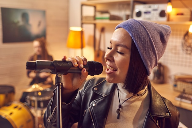 Foto bela jovem cantora cantando no microfone em um estúdio musical