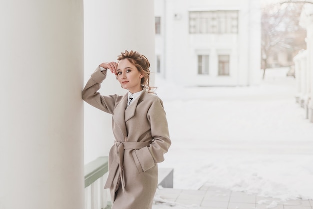 Foto bela jovem caucasiana entra com um casaco no inverno na cidade