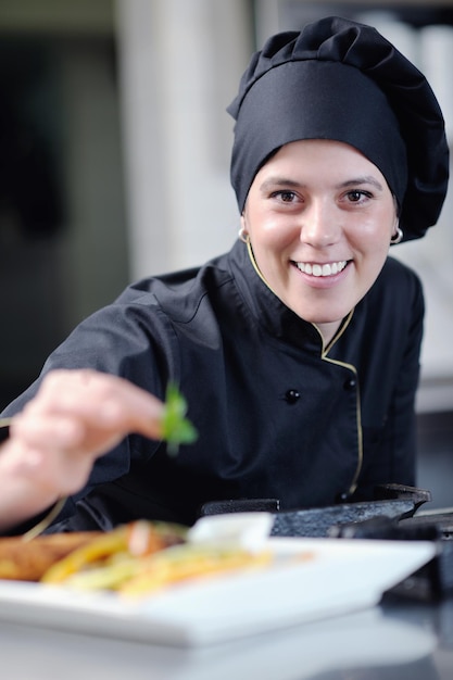 bela jovem chef preparar e decorar comida saborosa na cozinha