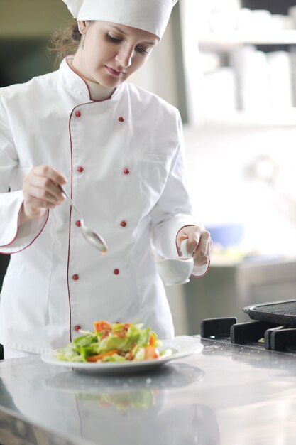 bela jovem chef preparar e decorar comida saborosa na cozinha