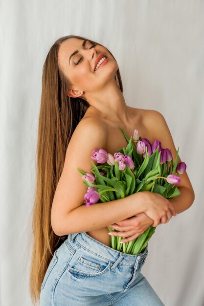 Foto bela jovem com cabelos longos segura um buquê de tulipas retrato de mulher em fundo branco