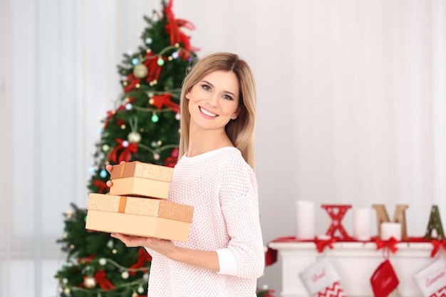 Bela jovem com caixas de presente em um quarto decorado para o natal