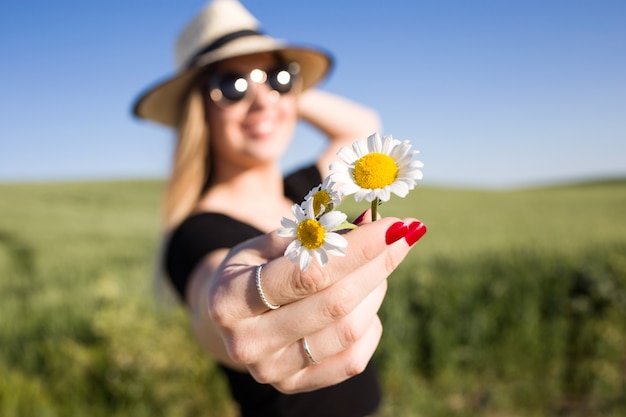 Bela jovem com flores desfrutando o verão em um campo.