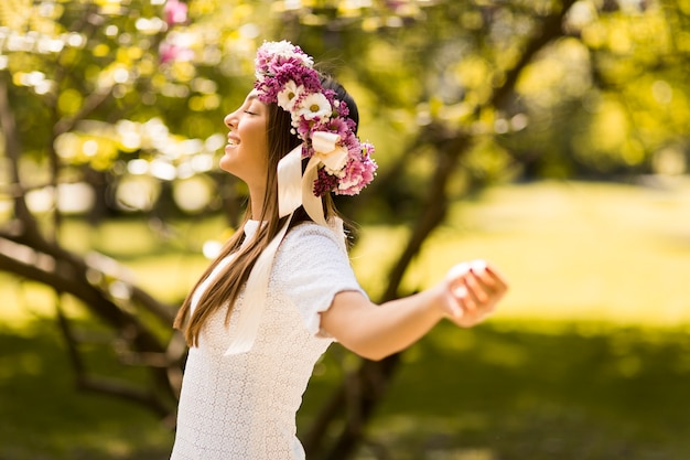Foto bela jovem com flores no cabelo em dia ensolarado de primavera