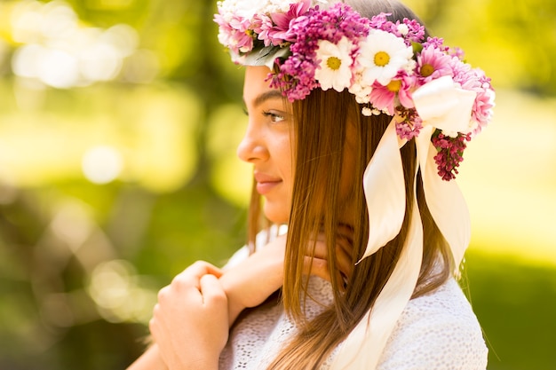 Bela jovem com flores no cabelo em dia ensolarado de primavera