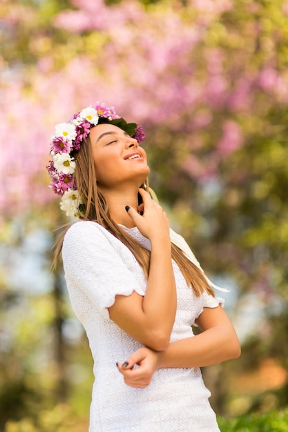 Foto bela jovem com flores no cabelo em dia ensolarado de primavera