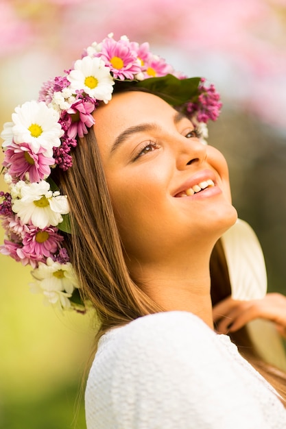 Foto bela jovem com flores no cabelo em dia ensolarado de primavera