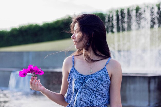 Foto bela jovem com flores roxas.