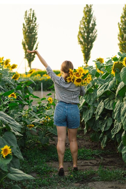 Foto bela jovem com girassóis desfrutando da natureza e rindo no campo de girassóis de verão