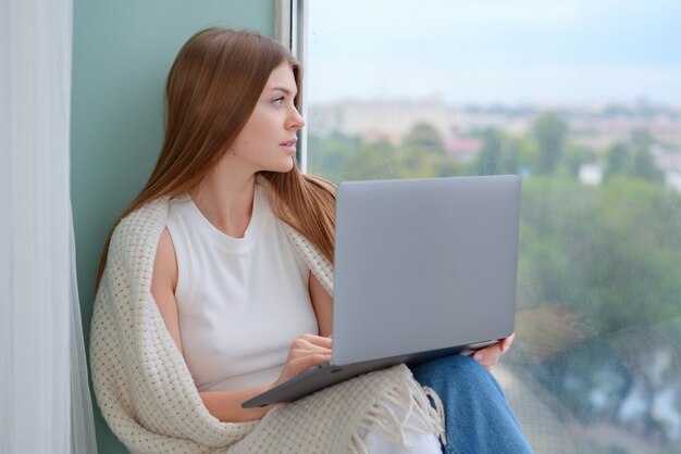 bela jovem com laptop em casa no sofá conversando sobre estilo de vida online
