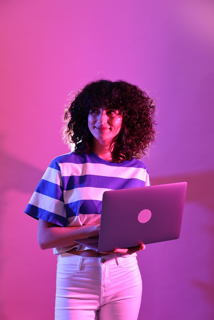 Foto bela jovem com laptop em fundo colorido em luzes de néon
