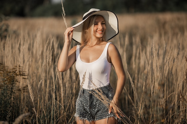 Bela jovem com um chapéu no campo de verão