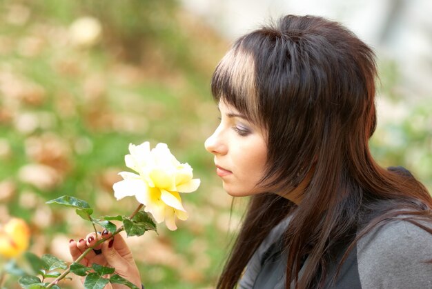 Bela jovem com uma rosa amarela no jardim